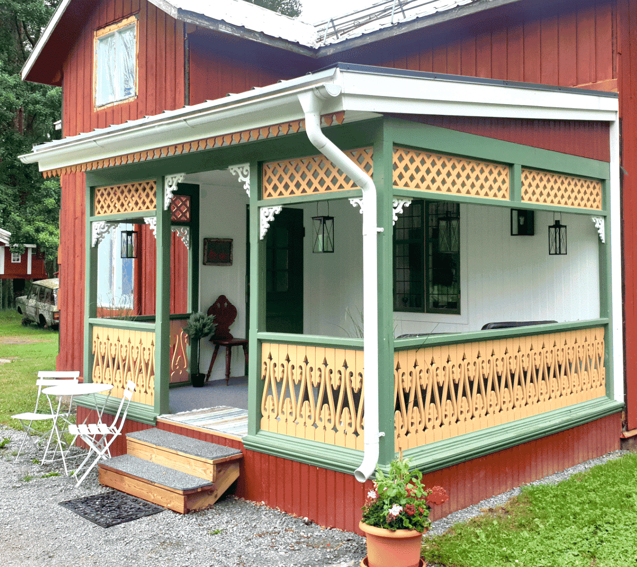A red Swedish house with traditional balusters and decorative brackets.