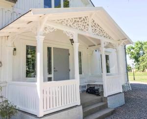 En klassisk vit farstukvist och farstubro med träkonsol 020 och fyllnadsdekor 030 från Gaveldekor. - En veranda med inspiration från sekelskifte och 1800-tal - Snickarglädje och nockdekor - tillverkad i Sverige - unik design