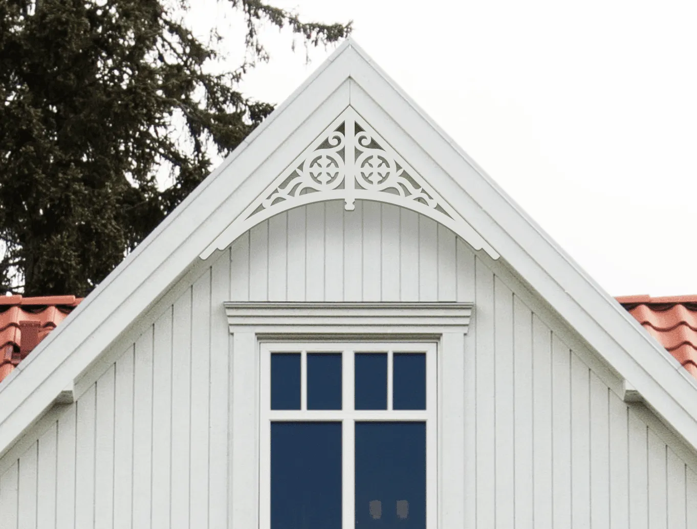 Gable pediment 004 - A white house with decorative wooden victorian millwork as house decoration for roof and gable end.