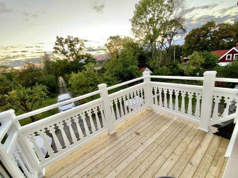 En vacker veranda med räcke av dubbla överliggare 040 - spjäla, ribba och räckesprofil till träräcke, balkong, altan och staket.