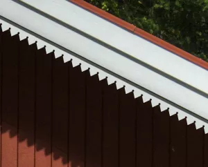 Ein rotes Haus, dekoriert mit dem Pfettenbrett 018. Hergestellt aus Holz in Schweden.