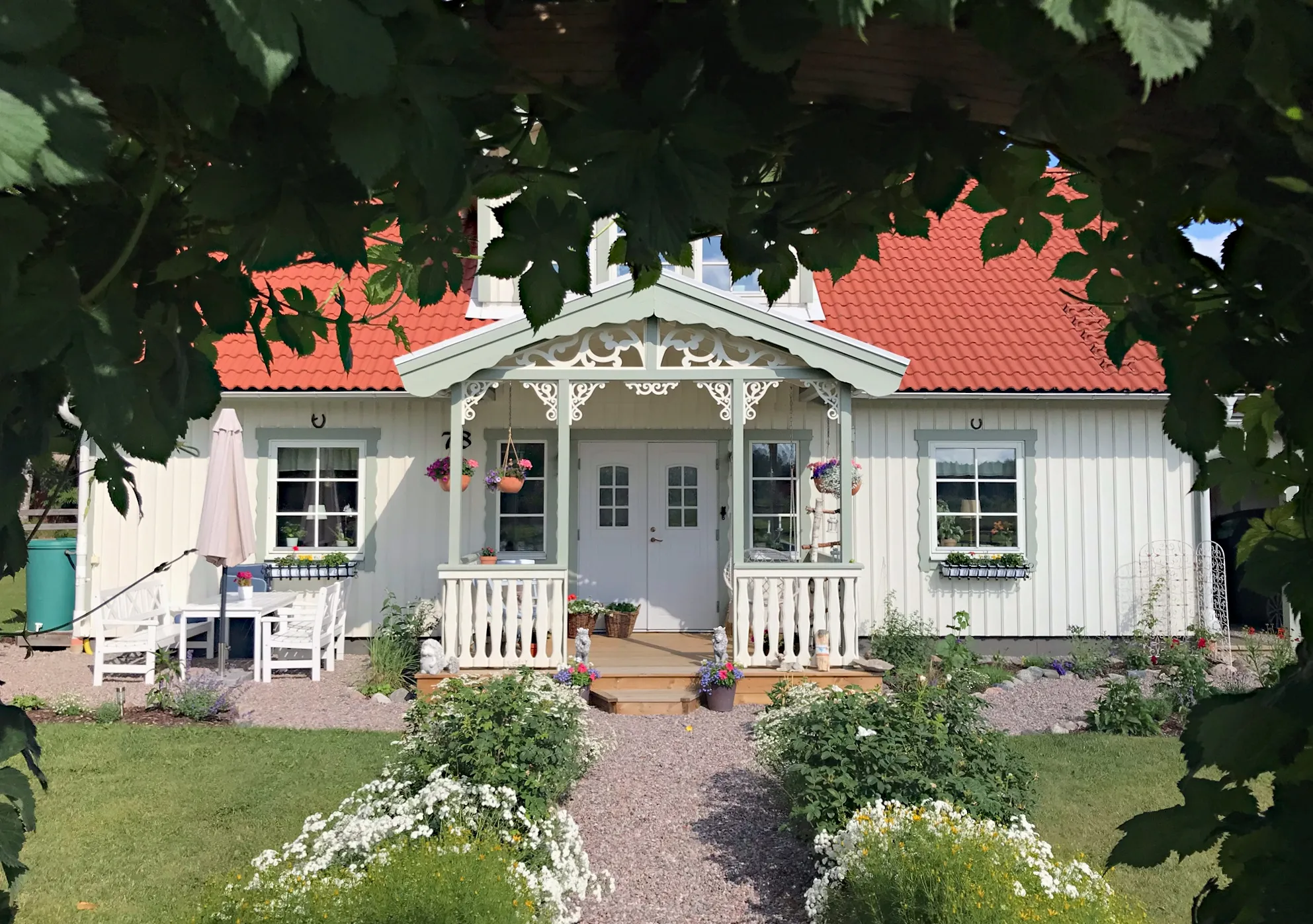 En klassisk vitt hus med ljusgrön veranda med träkonsol 020 från Gaveldekor. - En veranda med inspiration från sekelskifte och 1800-tal - Husdekoration och dekoration för taknock - tillverkad i Sverige - unik design