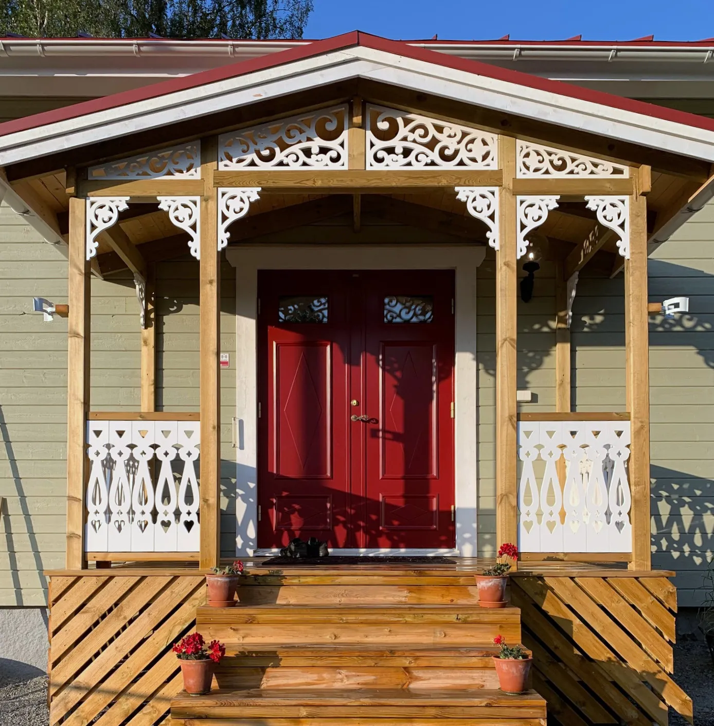 En klassisk gröngrått hus med ljusgrön veranda med träkonsoler för utomhusbruk från Gaveldekor. - En veranda med inspiration från sekelskifte och 1800-tal - Husdekoration och dekoration för taknock - tillverkad i Sverige - unik design