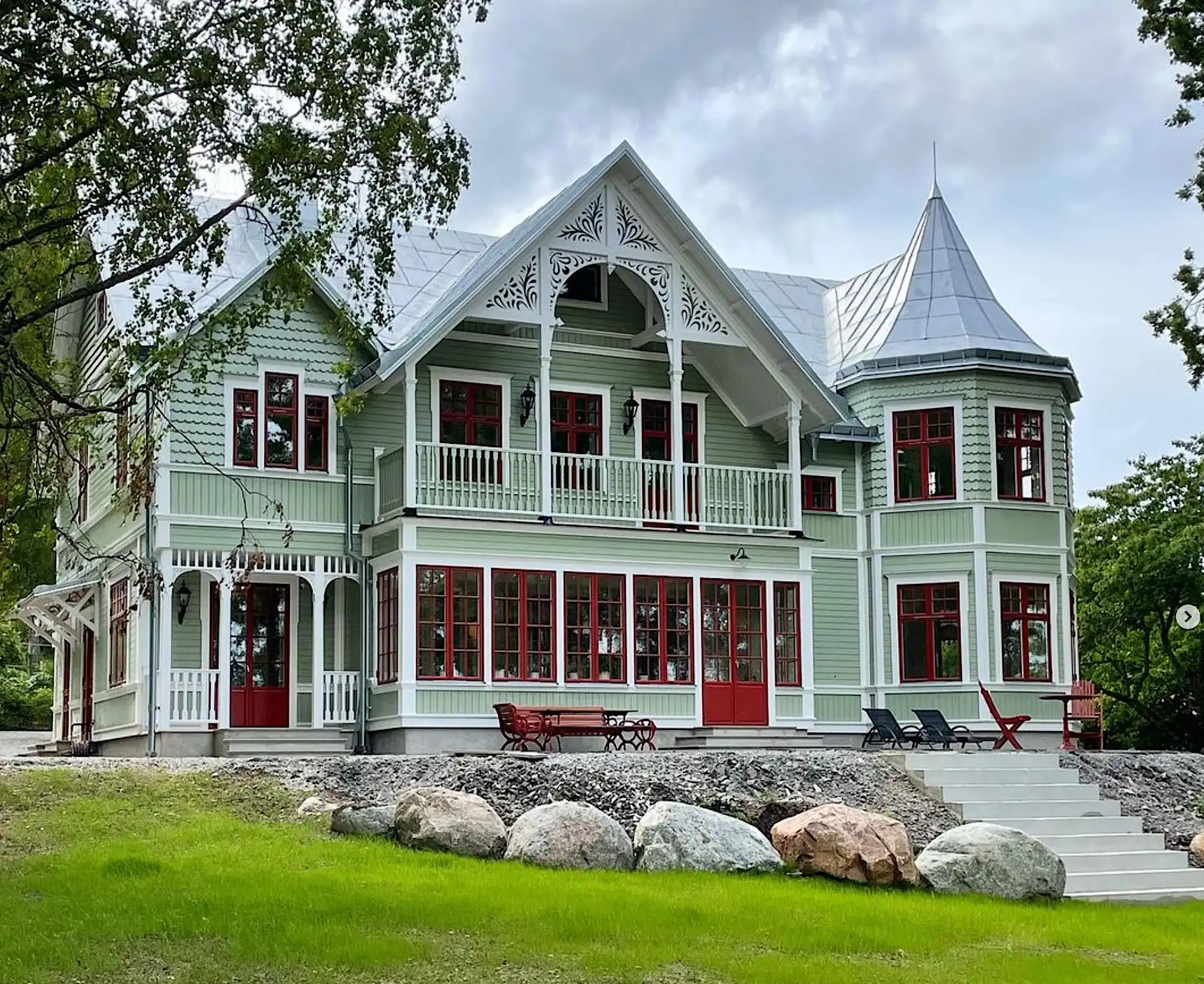 A typical Swedish Victorian green house with a porch and a lot of trim and moulding - wooden brackets - Red windows inspired by the turn of the century and 19th-century Jugendstil - Gaveldekor