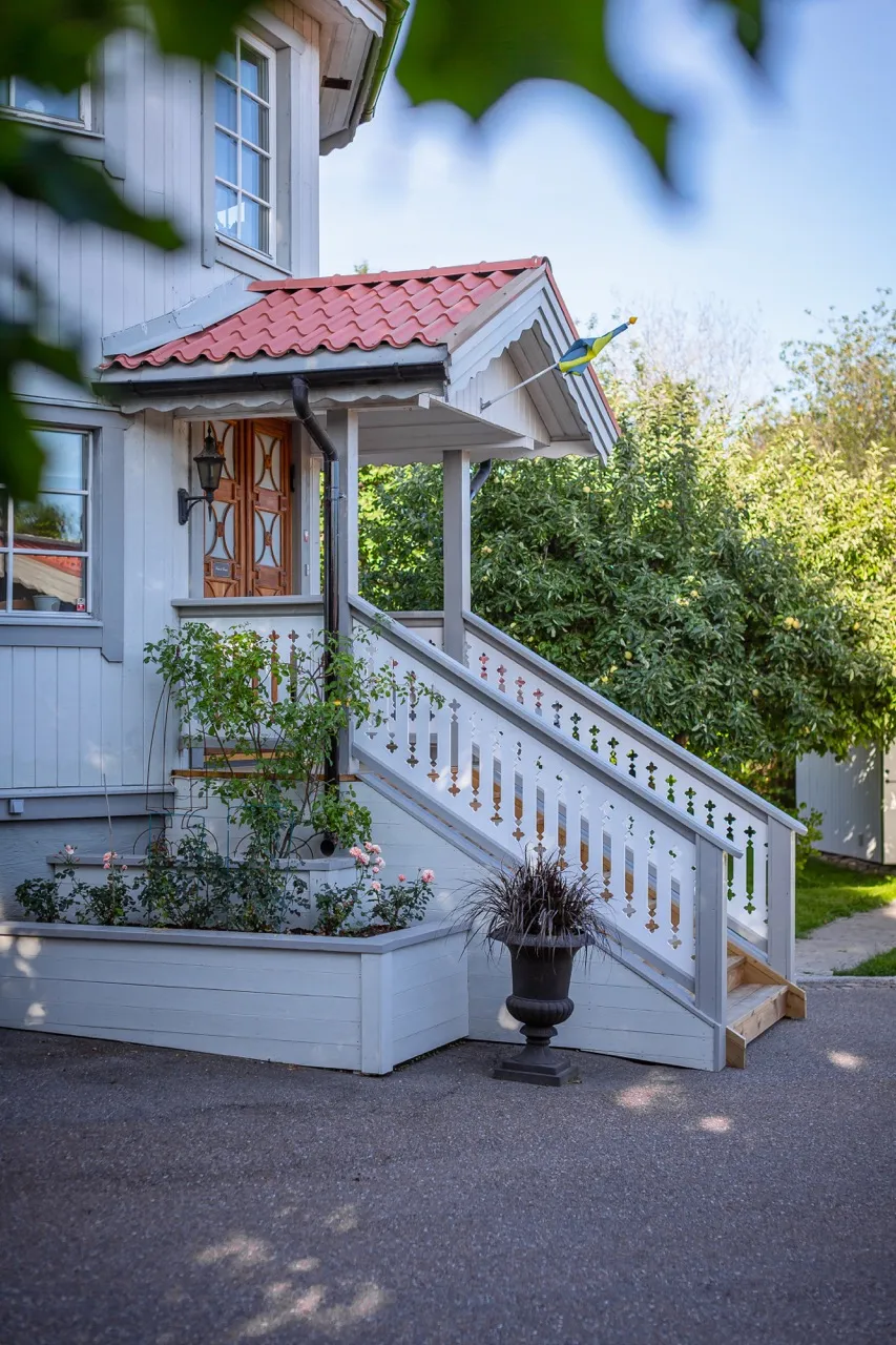 En elegant trappa till en farstukvist med vitmålade räcken i sekelskifte och 1800-tals stil - gammaldags med allmoge