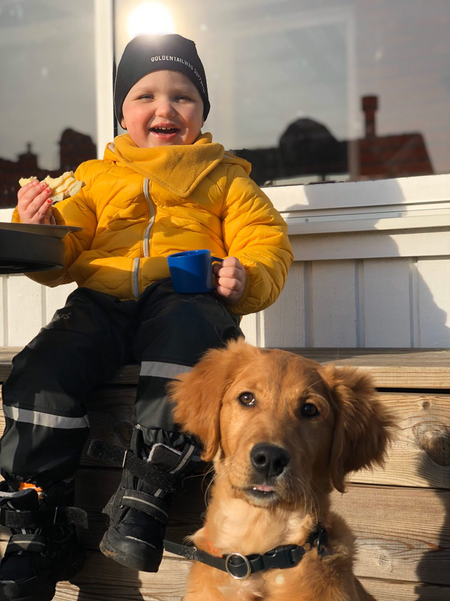 Barn med hund fikar i solen