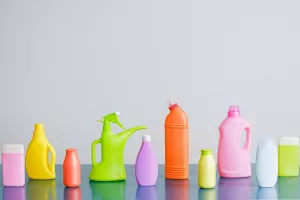 Flera plastflaskor uppradade på vit bakgrund  Flaskor i olika färger och storlekar för vätskor eller rengöringsmedel