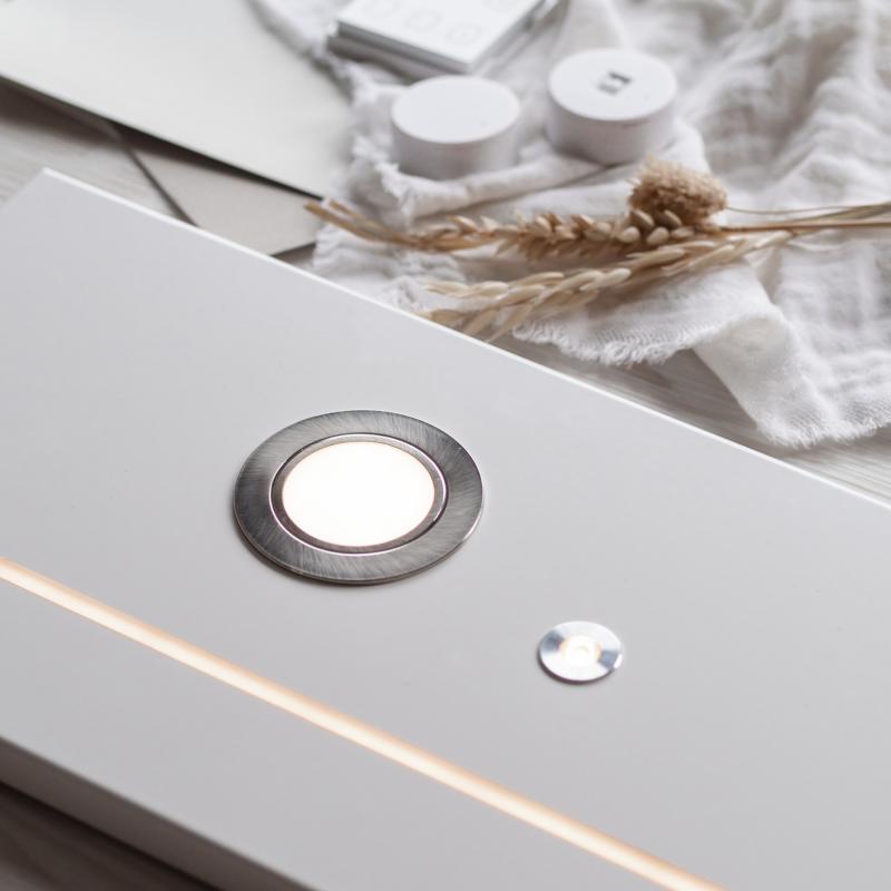 Två runda vita sensorer och en fyrkantig kontrollpanel placerade på en vit tygduk. Torkade veteax och grässtrån ligger bredvid komponenterna.