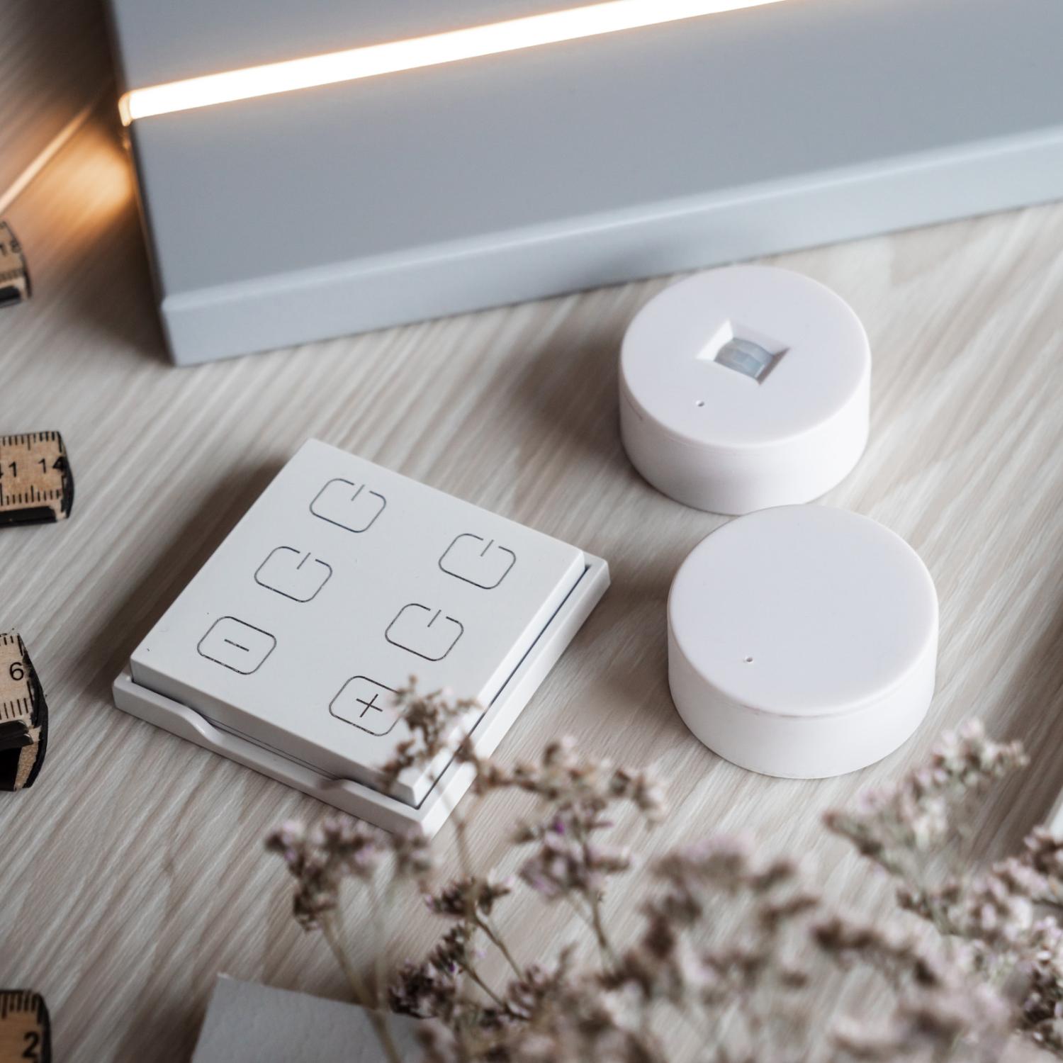 Två LED-spotlights monterade på en vit yta, omgivna av ljusa träprover och en ljus tygduk. En av spotlights är större än den andra.