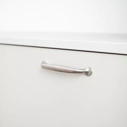Ett klassiskt kökshandtag i borstad nickel med två rundade ändar, monterat på en vit kökslåda.