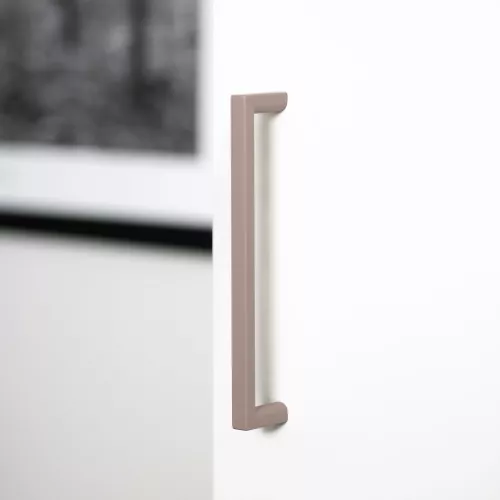 Rosa möbelhandtag från Linfalk, 128 mm, monterat på en garderobsdörr.