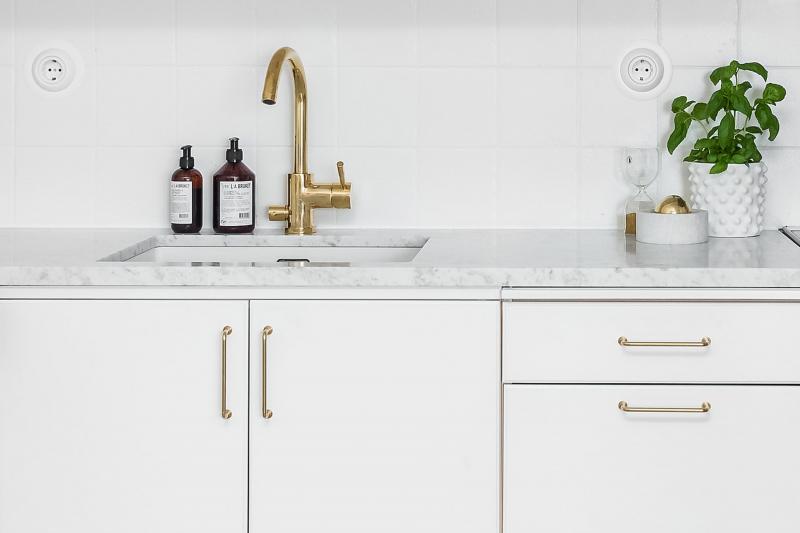 Modern white kitchen with brass handles and tap