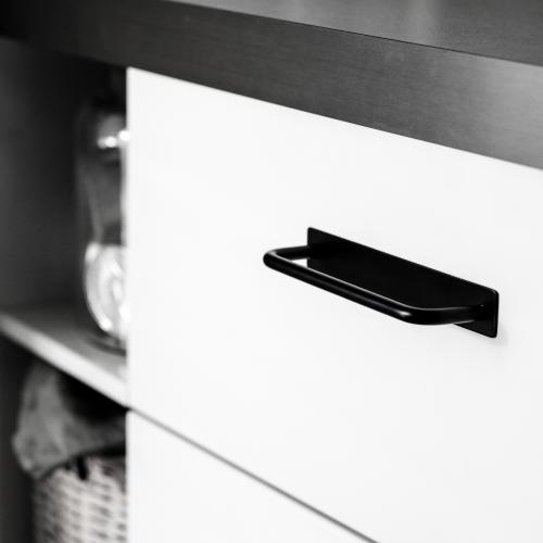 Minimalistiskt kökshandtag med täckbricka i nickel mot en vit kökslucka och grå bänkskiva