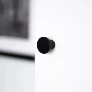 En svart garderobsknopp med en enkel och modern design. Knoppen har en slät, rund form och visas mot en vit bakgrund.