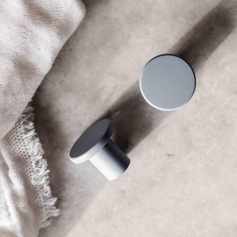 Två blå runda knoppar på en grå yta med en beige handduk bredvid.