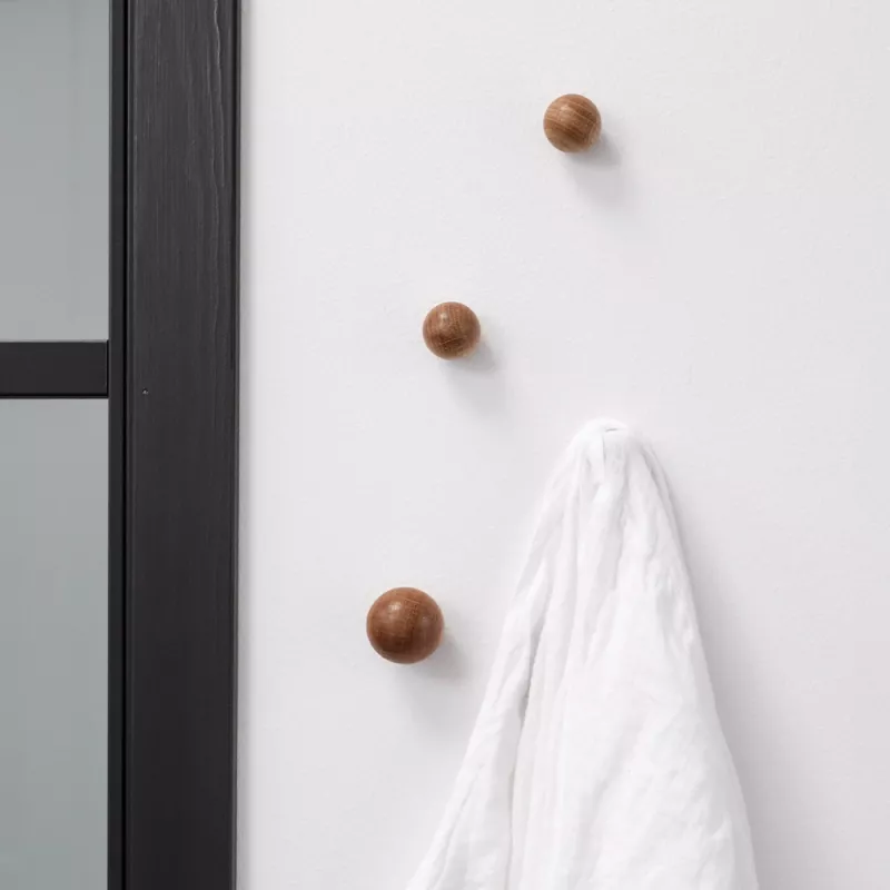 4st monterade runda träknoppar mot en vit vägg. På en knopp hänger en vit skjorta.