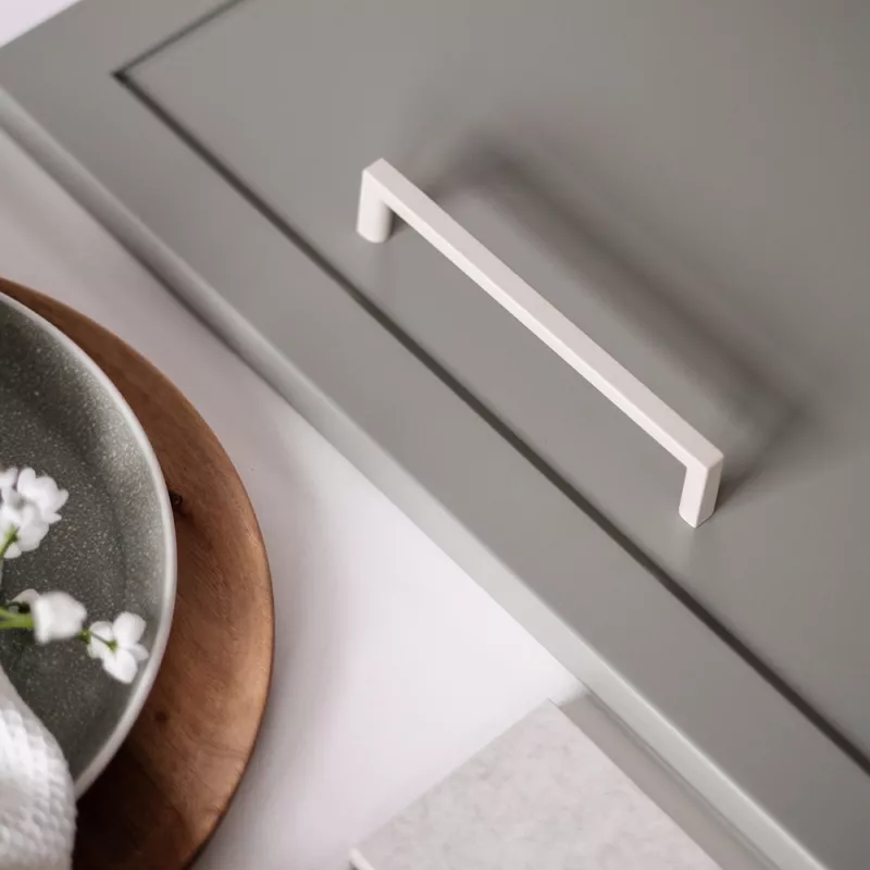 Rakt vitt handtag i NCS 2005-Y20R Sand Beige – minimalistiskt kökshandtag i pulverlack