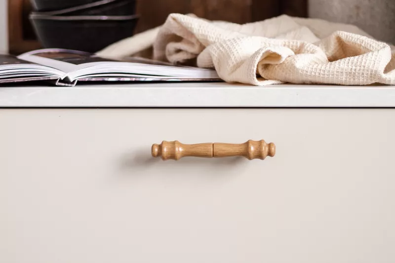 Oak handle on a beige kitchen drawer with book and towel