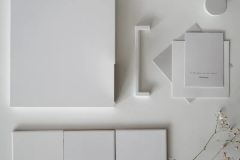 White kitchen fronts with discreet edge handles and pale materials in a minimalist palette