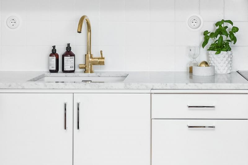 Modern white kitchen with nickel-free handles beside sink