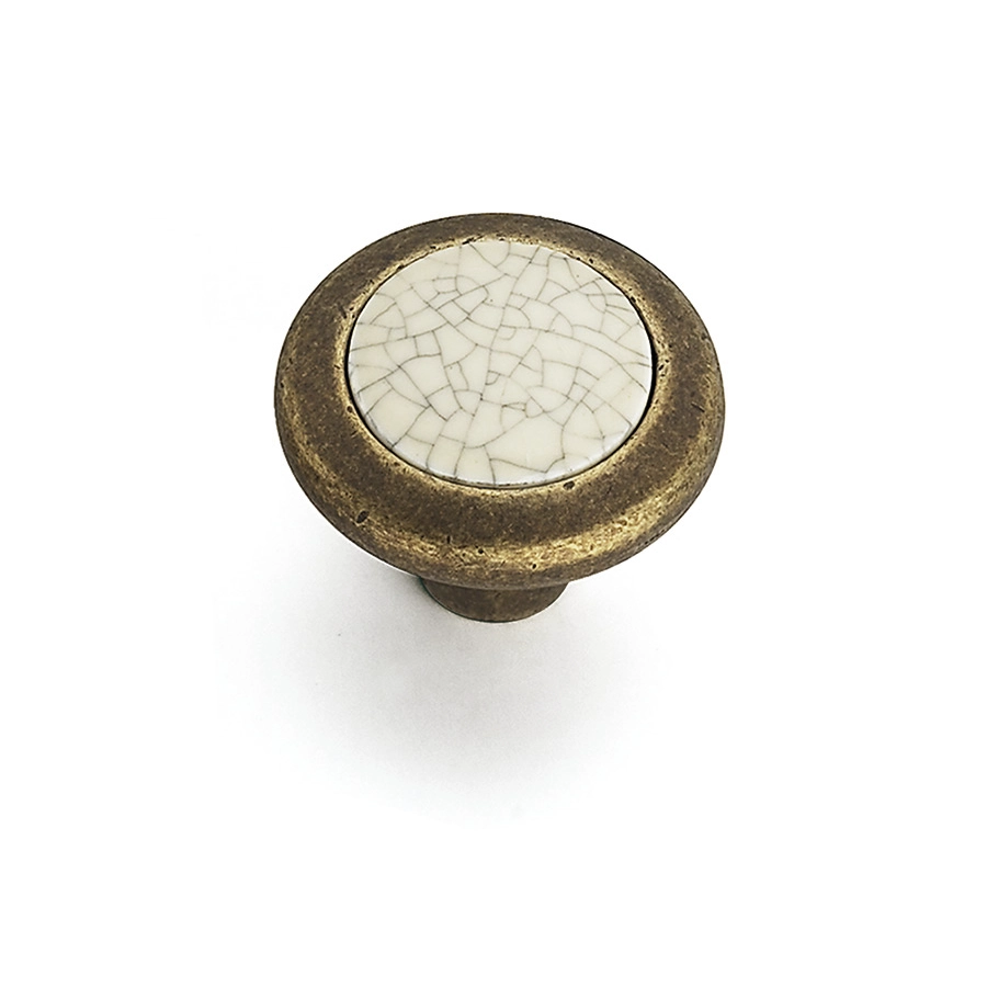 En närbild av en antik porslinsknopp med ett sprucket vitt mönster på en bronsbas.