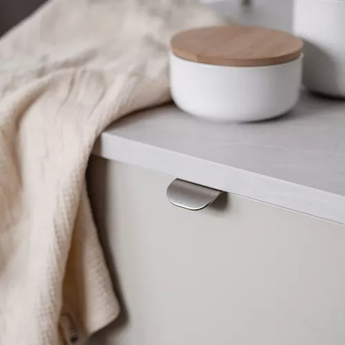 Ett profilhandtag i borstad krom med en smal och modern design, som ger ett stilrent och elegant utseende till möbler eller skåp.