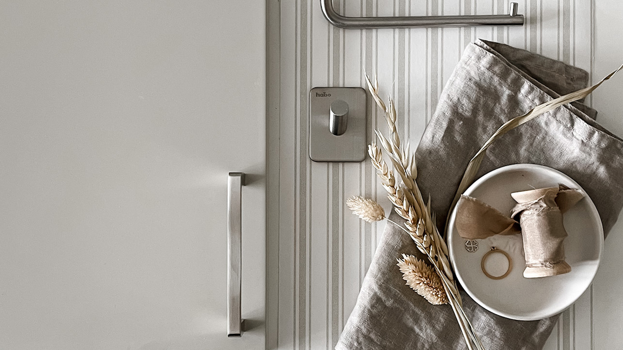 Självhäftande detaljer till ditt badrum. Kökshandtag i rostfritt mot beige lucka och självhäftande krok i beige inspirerande miljö