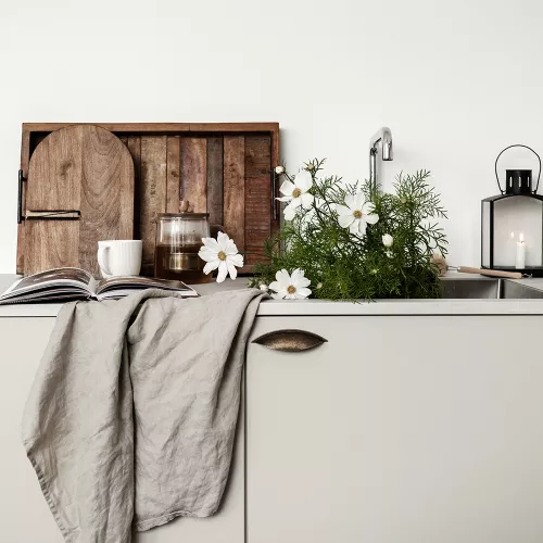 Antikt skålhandtag på en ljus skåpdörr, dekorerad med en grå duk och vita blommor.