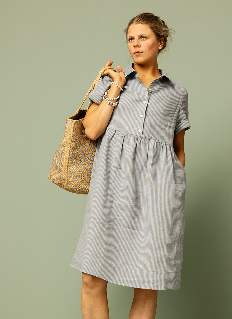 Ljusblå, blå smalrandig, randig linneklänning. Midiklänning, klänning med skjortkrage och knappar fram. Kort ärm och fickor. K&US linnekläder Stockholm