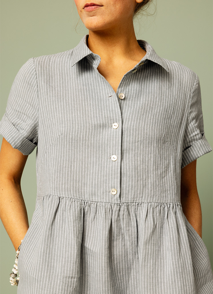 Ljusblå, blå smalrandig, randig linneklänning. Midiklänning, klänning med skjortkrage och knappar fram. Kort ärm och fickor. K&US linnekläder Stockholm