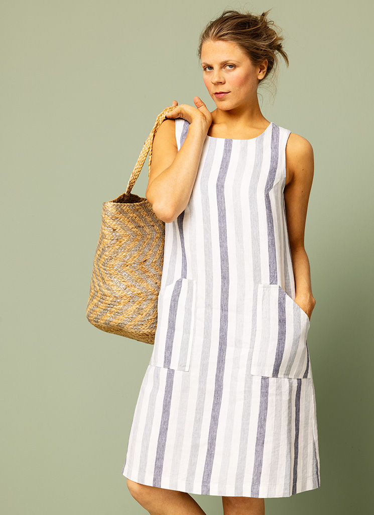 Blårandig, randig linneklänning med blå ränder på vit botten. Knälång midiklänning med stora fickor. K&US Kandus linnekläder Stockholm Södermalm