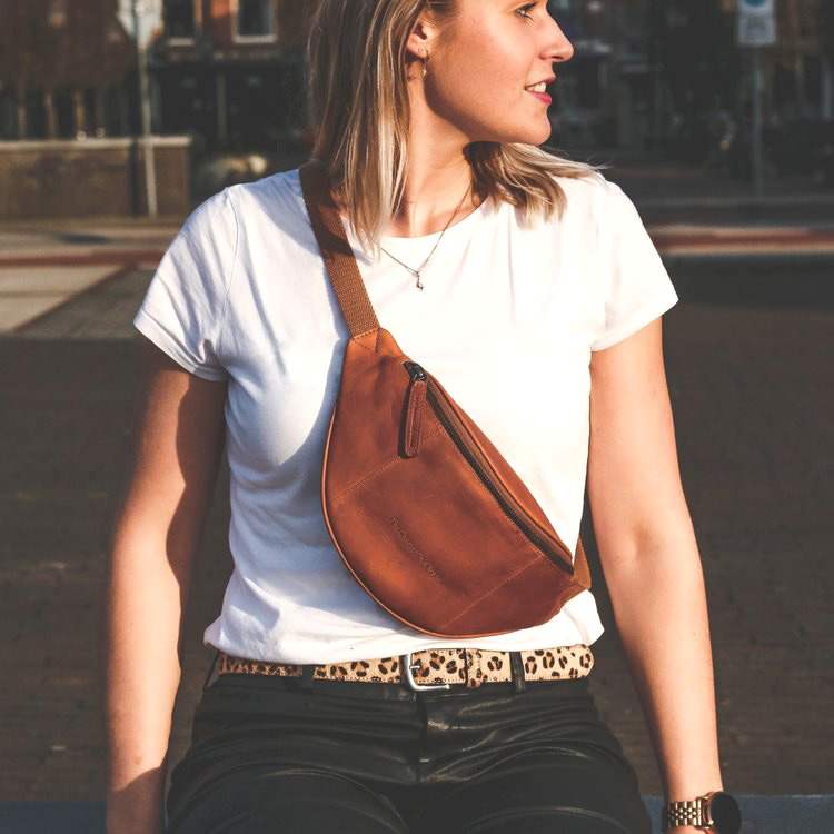 kvinna som står på gata i t-shirt och har en brun midjeväska i läder av modellen eden från varumärket the  chesterfield brand