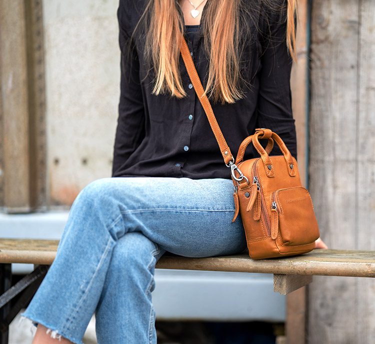 närbild på kvinna som bär brun axelremsväska i läder av modellen morena från varumärket the chesterfield brand