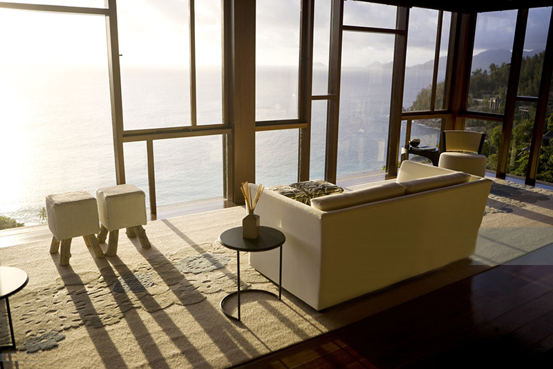 skinnsoffa står framför ett panoramafönster med soldränkt utsikt över ett hav