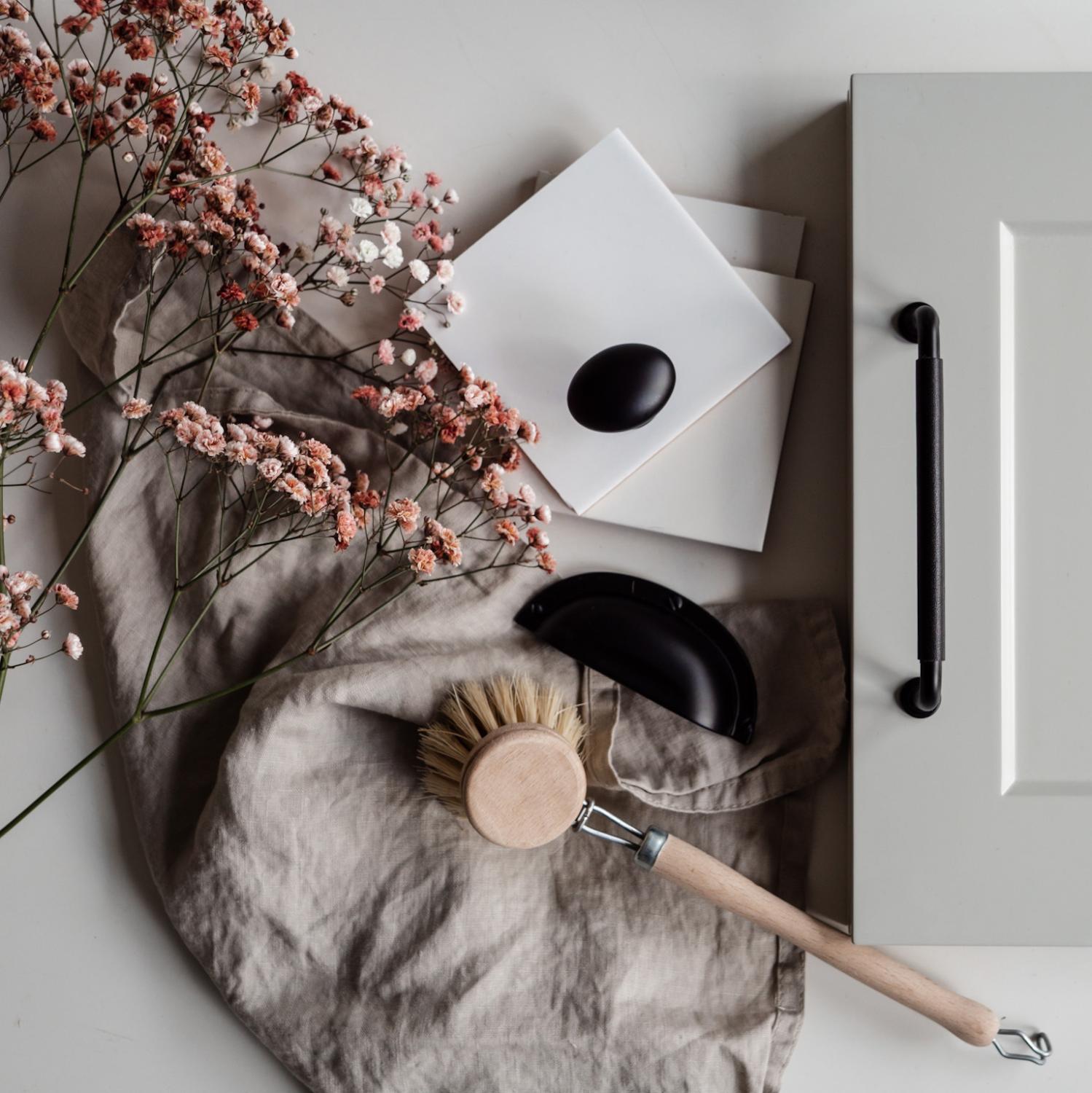 Svarta kökshandtag och knopp mot grå ramlucka och lantliga detaljer