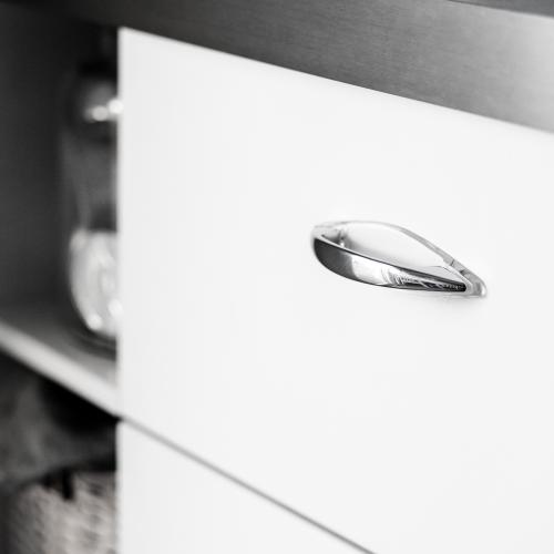 Handtag i stil 555 med inspiration från 50 talet mot en vit lucka och grå bänkskiva