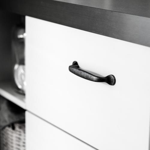 Kökshandtag i rustik antik oxidfinish mot en vit kökslucka och grå bänkskiva