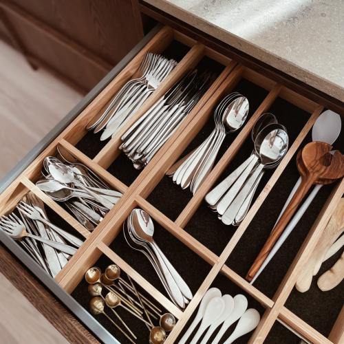 Närbild på besticklåda i ek i en mörkgrå kökslåda mot ljust trägolv och beige bänkskiva