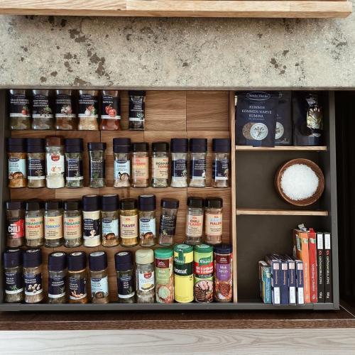 Kryddförvaring i ek fylld med kryddor i en mörkgrå kökslåda och en beige stenskiva.