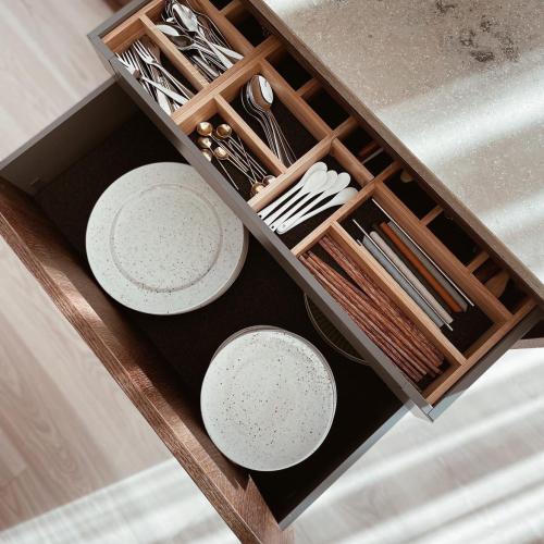 Lådmatta i filt och besticklåda i ek i en mörkgrå kökslåda mot ljust trägolv och beige bänkskiva