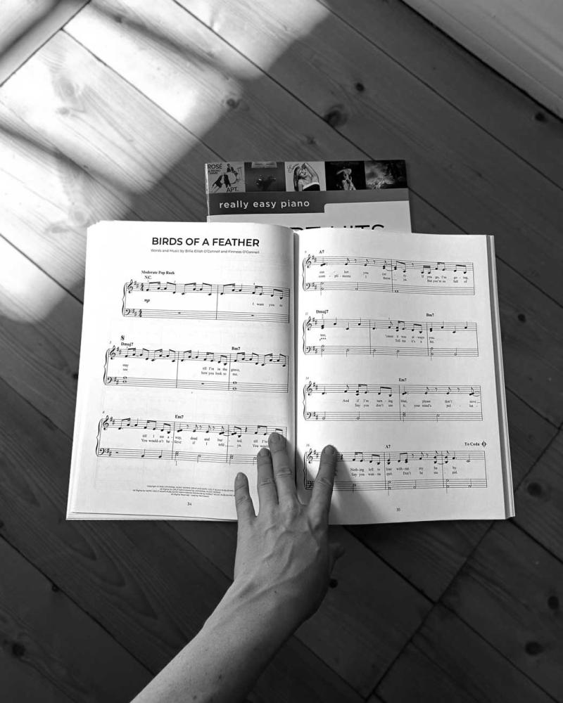 Easy Piano Chart Hits of 2024-2025, öppnad bok visar noterna till Birds of a Feather av Billie Eilish, svartvit.