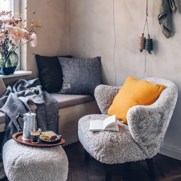 Mysig läshörna med mjuk fåtölj, linnekuddar, filt och blommor