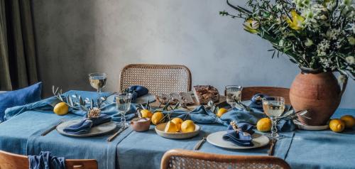 Ett vackert dukat bord med blå linnetextilier, dekorerat med citroner och blommor i en rustik vas