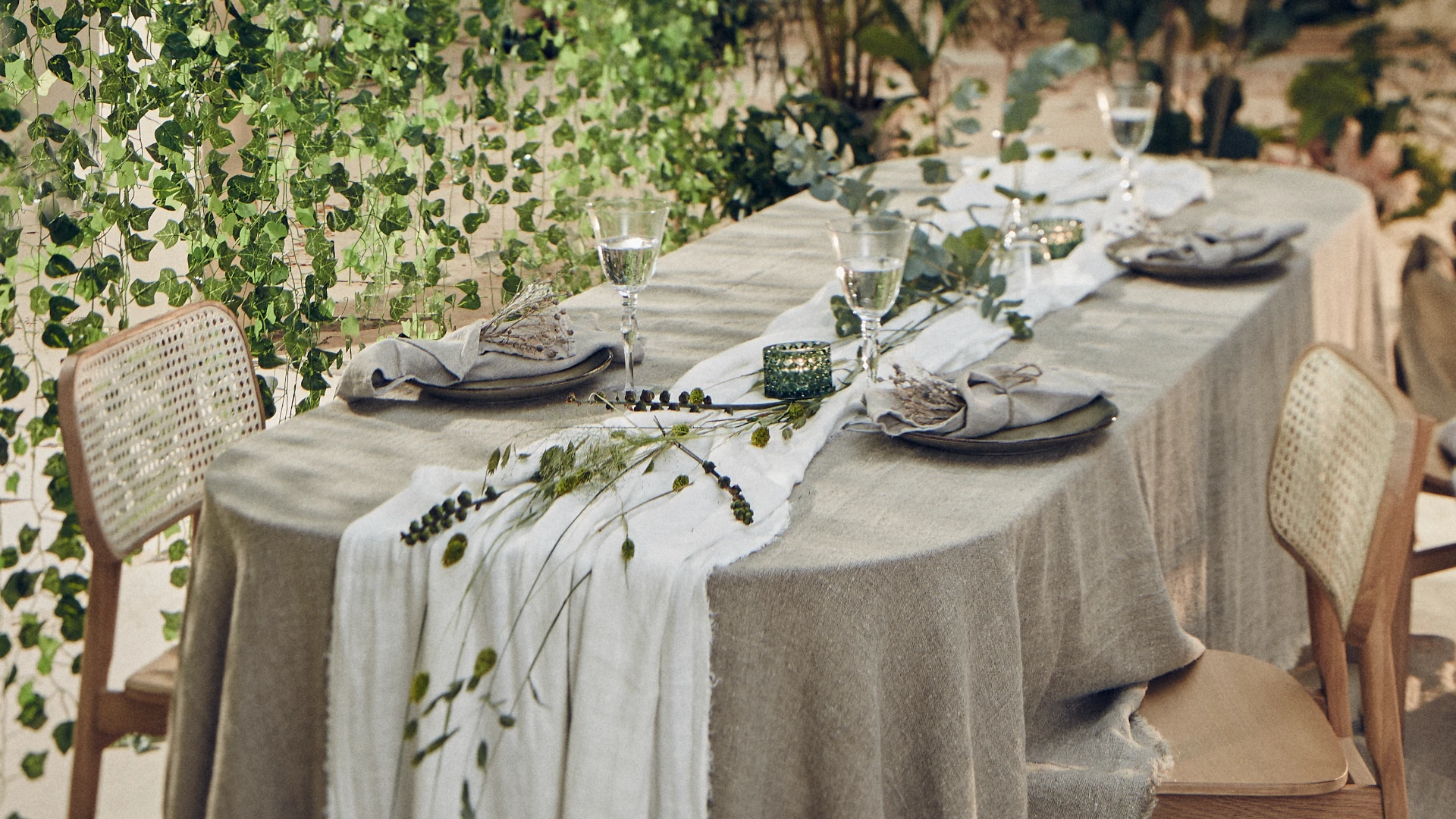 Elegant uppdukning för utomhusmiddag med grönska och neutrala linnetextilier.