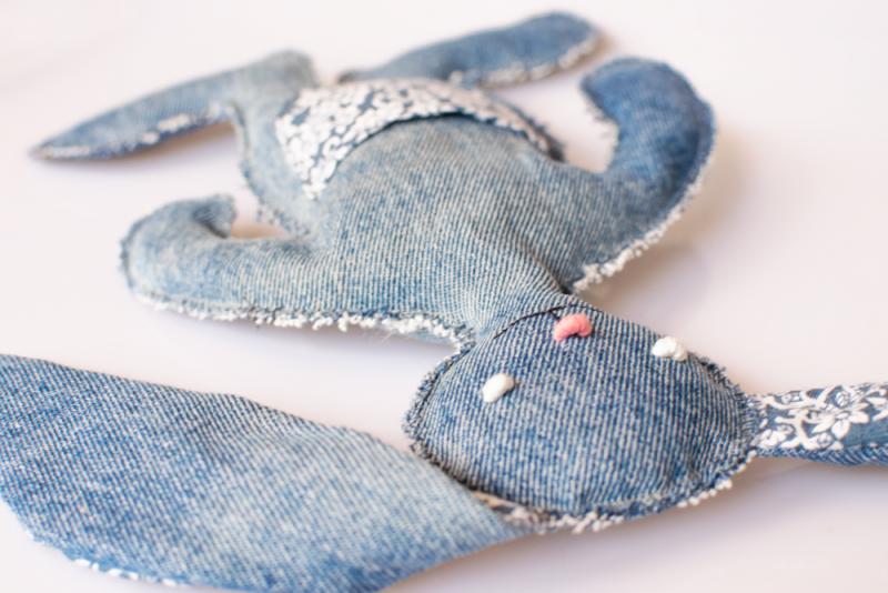 Hundleksak i denim med öron och magpåse i  blommönster, vita ögon och rosa nos.