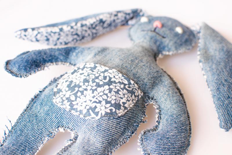 Hundleksak i denim med öron och magpåse i  blommönster, vita ögon och rosa nos.