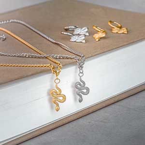 Halsband i guld och silver med hängsmycke i motiv av ormar.