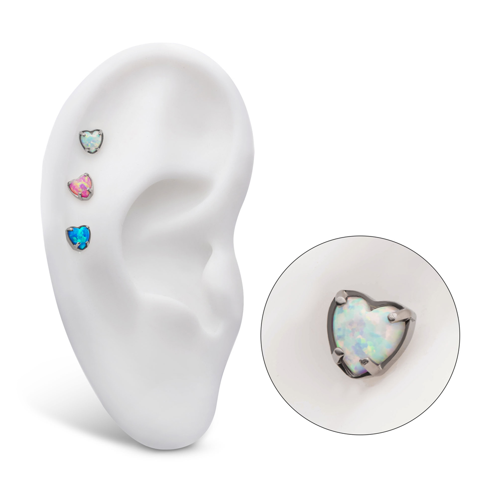 Piercingsmycke med vit opalit. Tre hjärtformade toppar i nickelfritt titan placerade i helix på ett vitt displayöra.