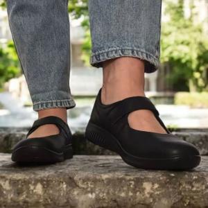 Miljöbild på en person som står på stentrappor utomhus iklädd helsvarta Jomos Allegra D 2020 komfortskor i skinn och ljusblå jeans.