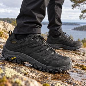 Svarta Merrell Moab 3 Synthetic Ice WP herrskor på våta klippor vid en sjö. Vattentäta vandringsskor med snabbsnörning och Vibram-yttersula, tillgängliga upp till storlek 50.